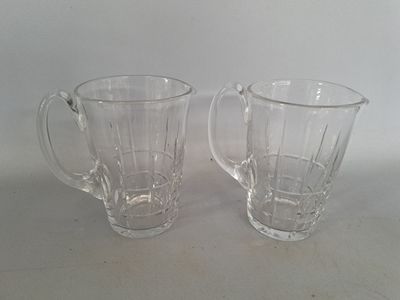 une paire de mugs en verre transparent posés sur une table blanche