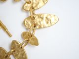 a close up of a gold necklace on a white surface