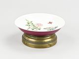 a small bowl on a stand with a flower design on it