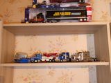 de nombreux camions miniatures et camions posés sur une étagère dans une pièce