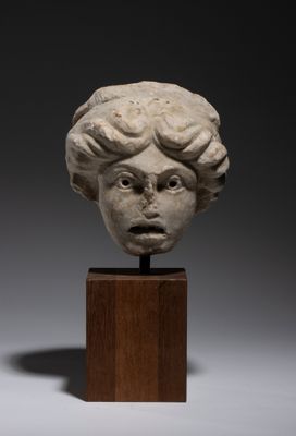 a white marble head of a child on a wooden stand