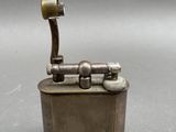 an old metal lighter with a metal handle on a gray surface