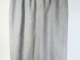 grey skirt hanging on a hanger against a white wall