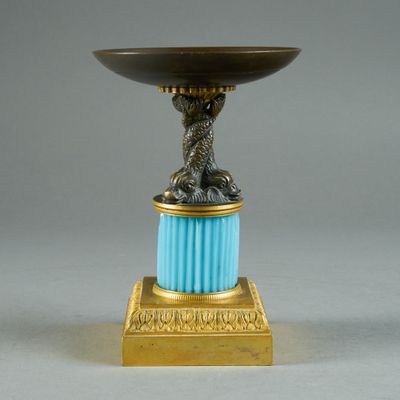 a gold and blue vase with a bird on top of it