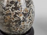 a stone egg sitting on a stand on a white surface