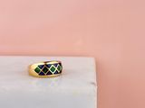 une bague en or sertie de diamants noirs et verts sur fond rose