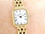 a woman ' s wrist that has a gold watch on it