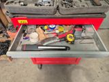 une boîte à outils rouge contenant des outils, dans un garage