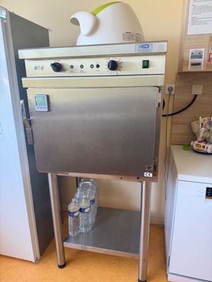 a stainless steel oven sitting on a stand next to a refrigerator