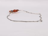 a close up of a silver bracelet with an orange bead on it