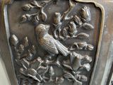 a metal vase with a bird and flowers on it