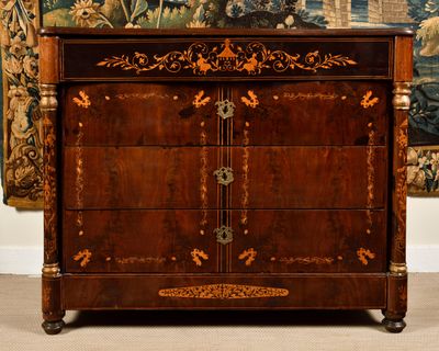 une commode ancienne dans une pièce où est accrochée une tapisserie au mur