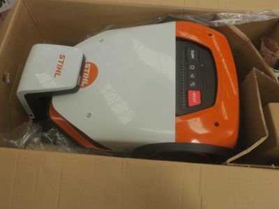 une tondeuse à gazon orange et blanche dans un carton