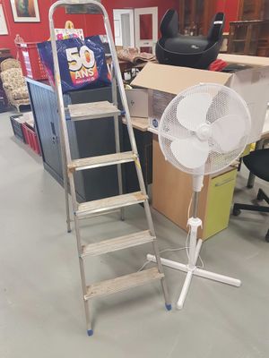 a ladder that is leaning against a wall next to a fan