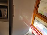 a white refrigerator in the corner of a kitchen next to a window