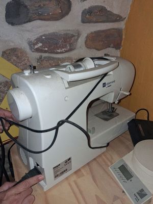 une machine à coudre blanche posée sur une table près d'un mur de briques