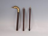 three wooden and brass canes and a cane stick on a white surface