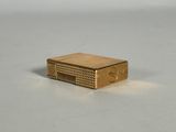 une photo d'un briquet doré posé sur une table blanche