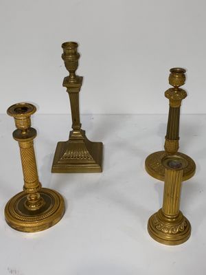 trois bougeoirs en laiton posés sur une surface blanche, sur fond blanc