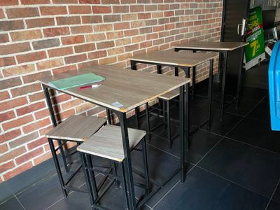 trois tables et deux tabourets devant un mur de briques