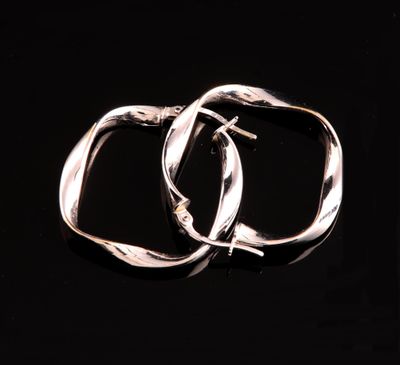 une paire de boucles d'oreilles créoles en argent sur fond noir