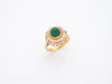 gros plan d'une bague en or avec une pierre verte