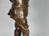 bronze figurine of a boy holding a bird on a pedestal