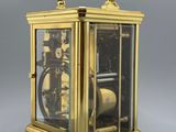 a small brass clock with a glass case on it