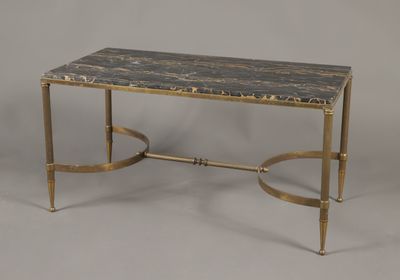 une photo d'une table basse au plateau en marbre et aux pieds en laiton