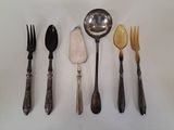 Plusieurs cuillères et fourchettes sont alignées sur une table