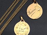 two gold medallions with the names of two people on them