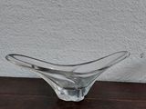 un bol en verre posé sur une table en bois, avec un mur blanc en arrière-plan