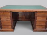 un bureau en bois avec un plateau en verre vert et des tiroirs