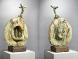 two sculptures of a man and a woman sitting on top of a white pedestal