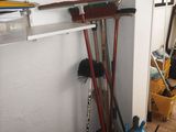 brooms, mops, and buckets are lined up against a wall in a room