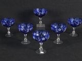 six blue glass goblets sitting on top of a black table