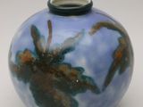 un vase bleu et brun posé sur une surface blanche
