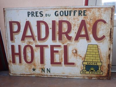 un panneau rouillé sur lequel on peut lire « Hôtel Padirac »