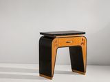 un tabouret noir et en bois, avec une assise noire posée sur une surface blanche