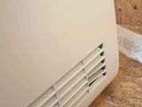 a white air conditioner sitting on the floor next to a wall