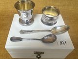 une tasse et une cuillère en argent posées sur une boîte blanche
