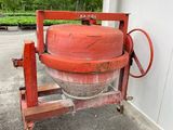 une bétonnière rouge posée sur un socle à l'extérieur
