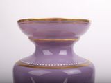 a purple vase with a gold rim sitting on a table