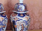 two vases sitting on a table with a wallpaper behind them