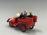 two figurines of men riding in a red car