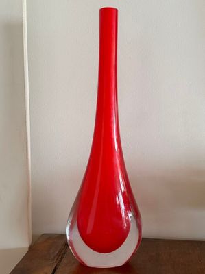 a red vase sitting on top of a wooden table