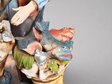 a figurine of a man sitting on a pot with fish