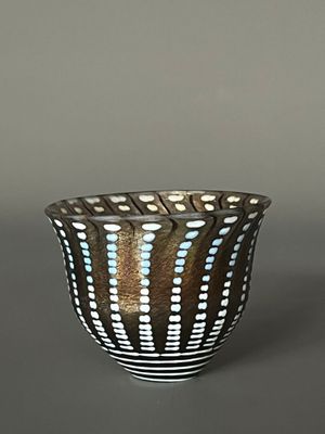 un bol noir et blanc parsemé de petits points bleus
