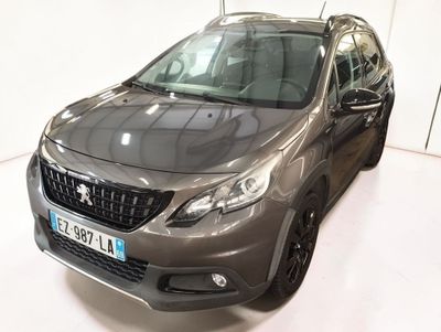 La voiture grise est garée dans une pièce blanche au sol blanc.