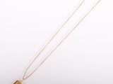 un collier plaqué or avec un pendentif de forme carrée monté sur une chaîne